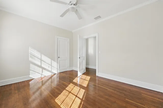 a view of a bedroom with wooden floor and fan