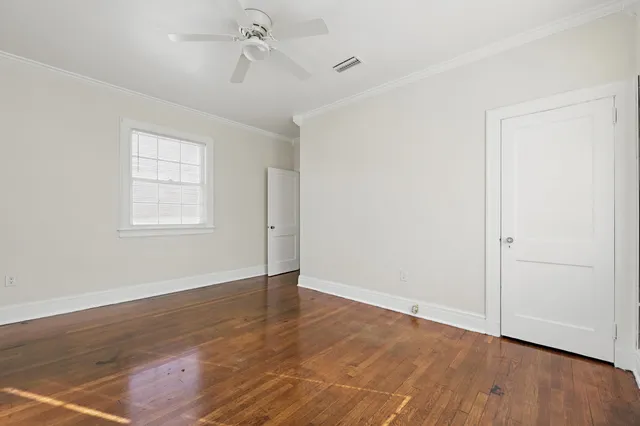 an empty room with wooden floor chandelier fan and windows