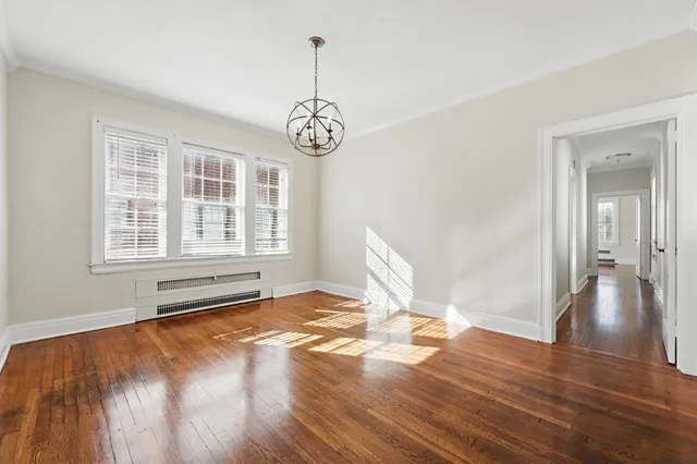 a view of an empty room with wooden floor and windows