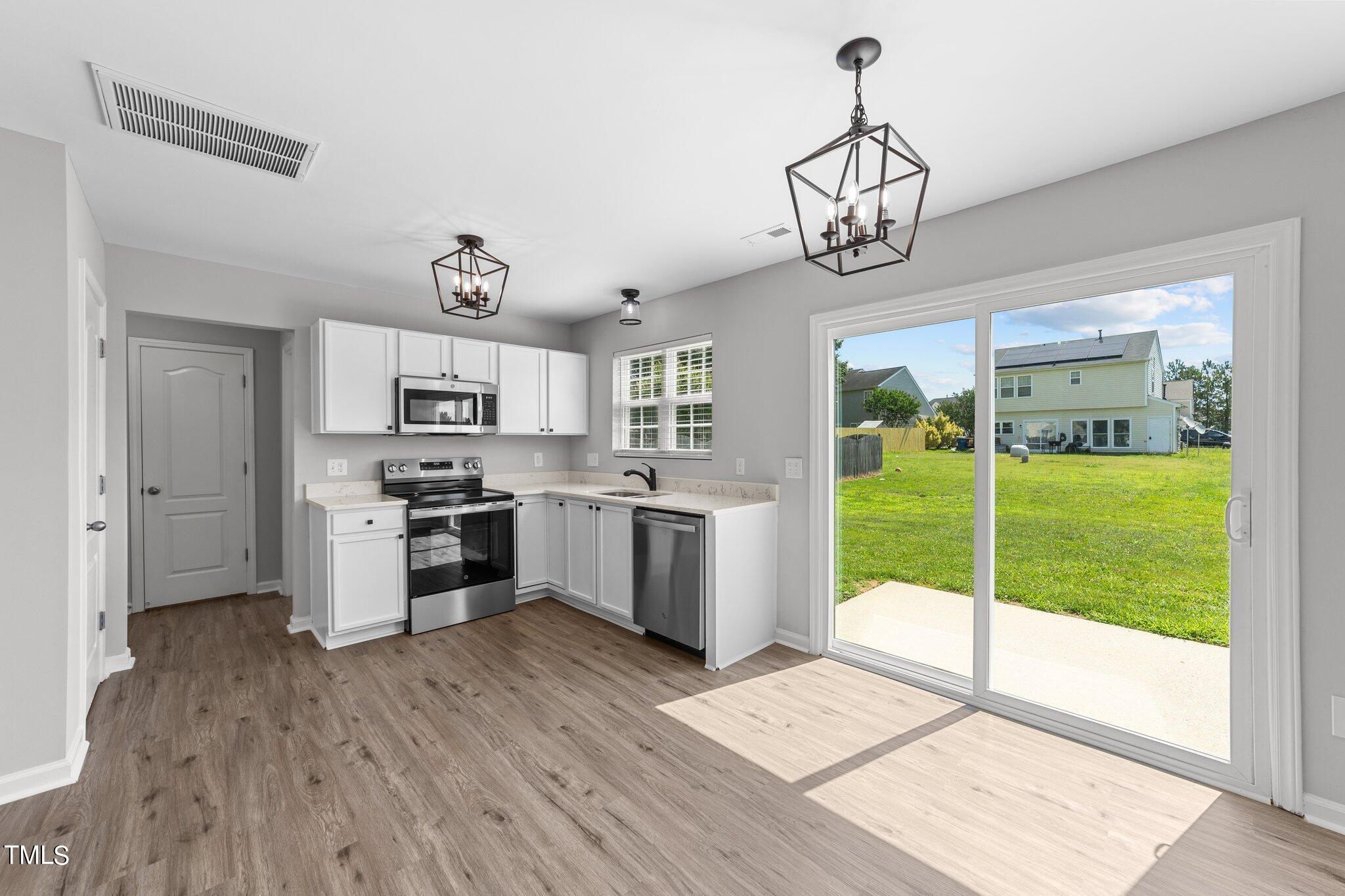 2909 Hayling Drive Raleigh, NC 27610 - Photo 11 of 35 a kitchen with stainless steel appliances kitchen island granite countertop a stove a refrigerator a sink dishwasher and white cabinets with wooden floor