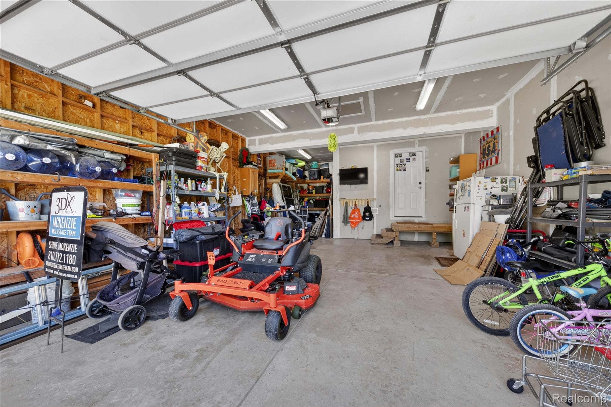 9191 Judd Road Fowlerville, MI 48836 - Photo 73 of 74 Spacious garage featuring a concrete floor, exposed wood framing, and fluorescent lighting