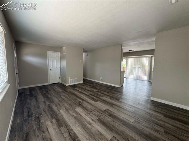 4420 Galley Road Colorado Springs, CO 80915 - Photo 11 of 20 Living room with dark wood finished floors, baseboards, and a textured ceiling
