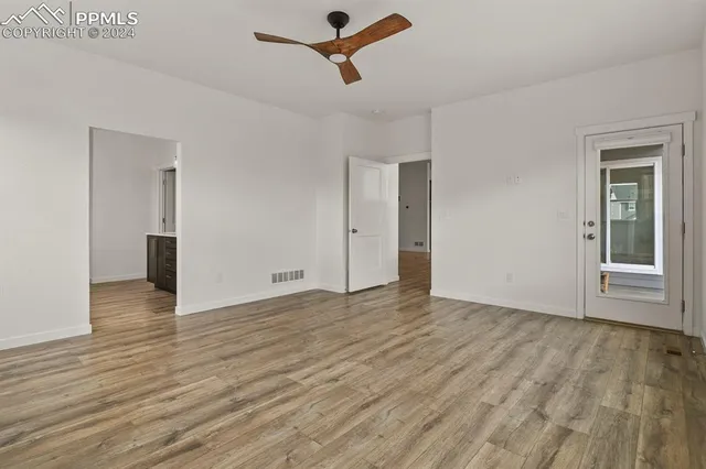 an empty room with wooden floor and windows