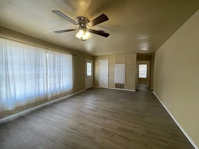 a view of an empty room with window and wooden floor