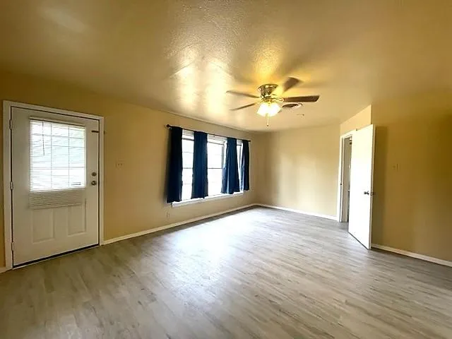 a view of an empty room with window and wooden floor