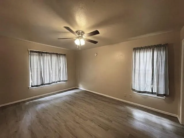 an empty room with windows and ceiling fan