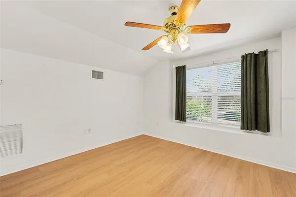 a view of an empty room with window and chandelier fan