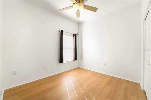 an empty room with a chandelier fan and windows