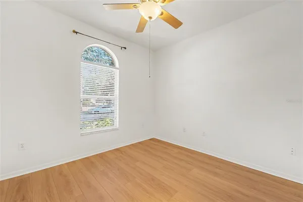 an empty room with a chandelier fan and windows