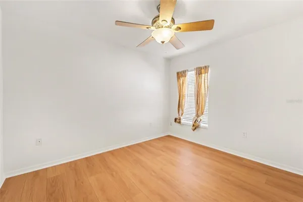 an empty room with a window and a fan