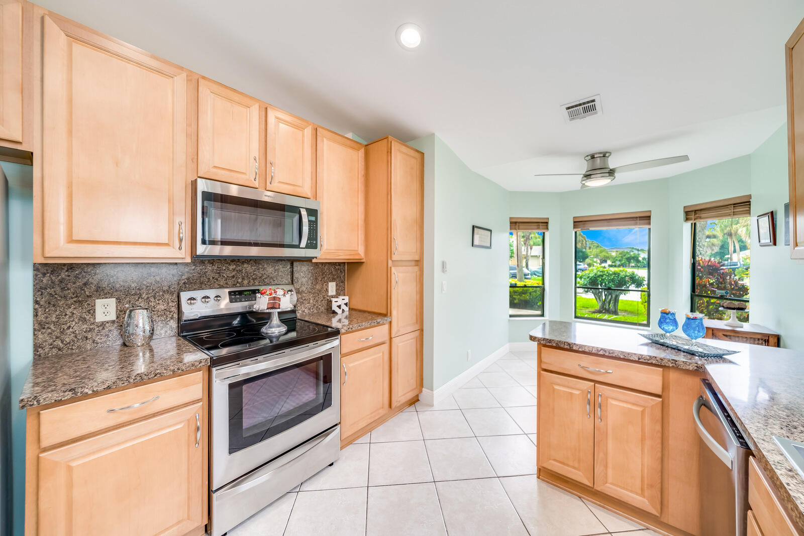 23250 Sedawie Drive Boca Raton, FL 33433 - Photo 20 of 42 a kitchen with kitchen island granite countertop a stove top oven a sink a counter space and cabinets