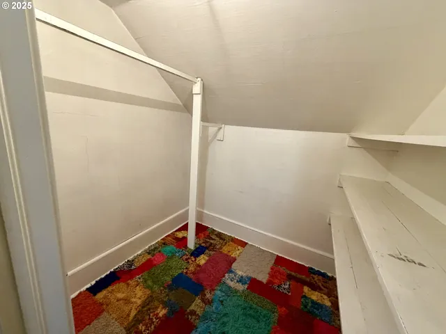 a view of an empty room with a window and a kitchen