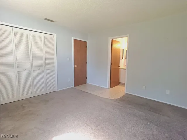 a view of an empty room with window and closet area