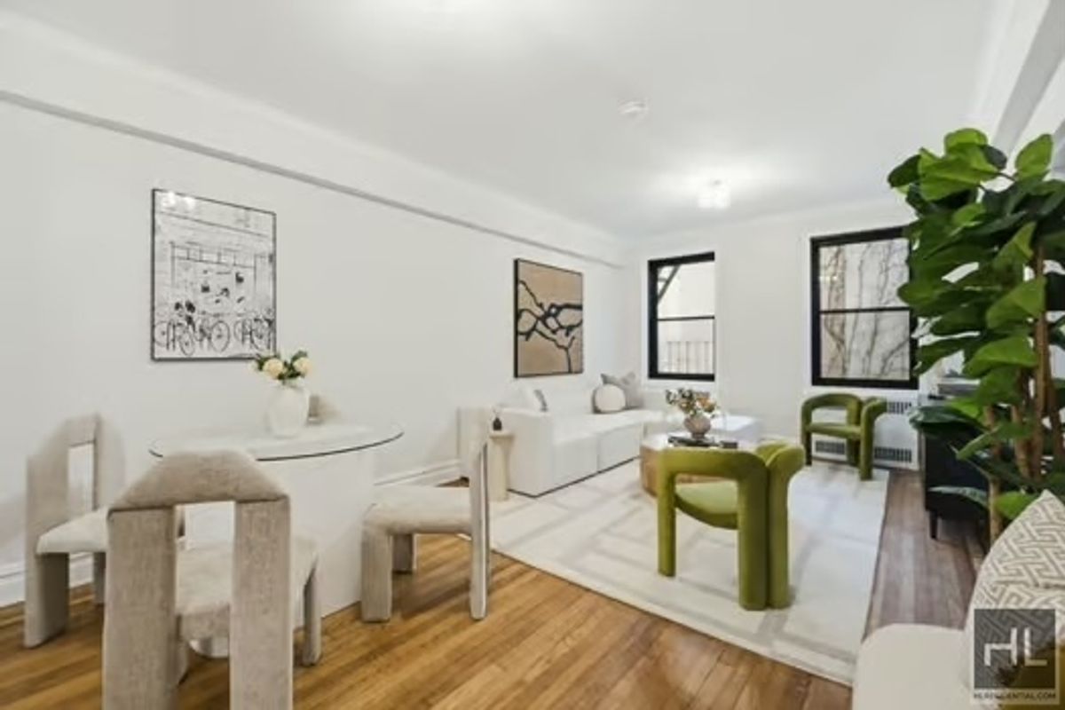 a living room with furniture a potted plant and open kitchen view