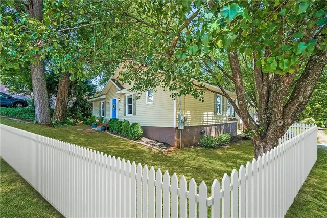 a view of a house with a small yard and large trees