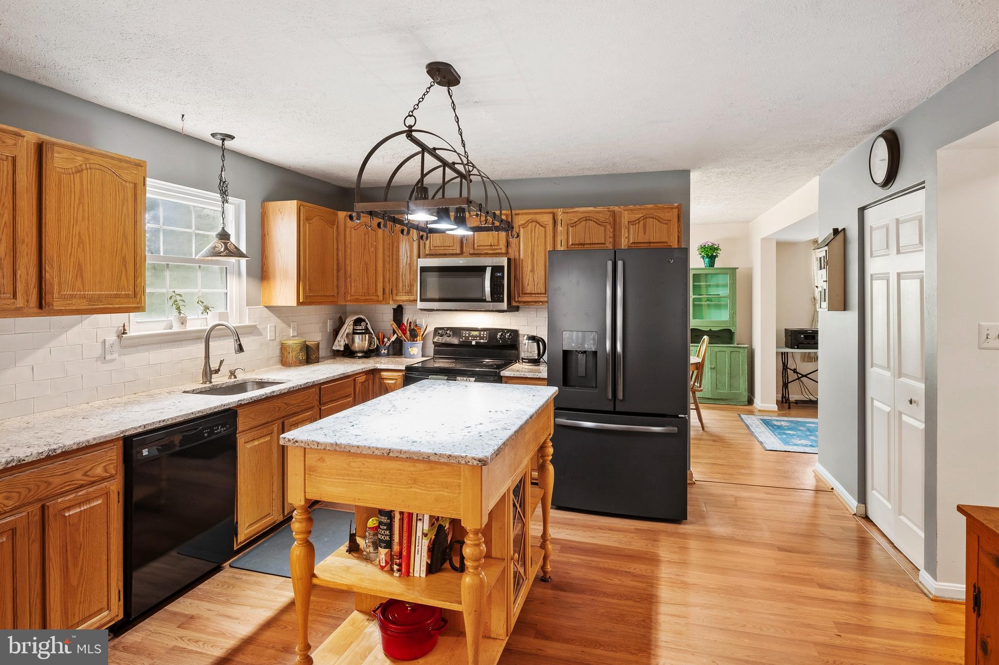 6415 Michael Elizabeth Way Hanover, MD 21076 - Photo 11 of 32 a kitchen with stainless steel appliances granite countertop a refrigerator a sink dishwasher a stove and a dining table with wooden floor