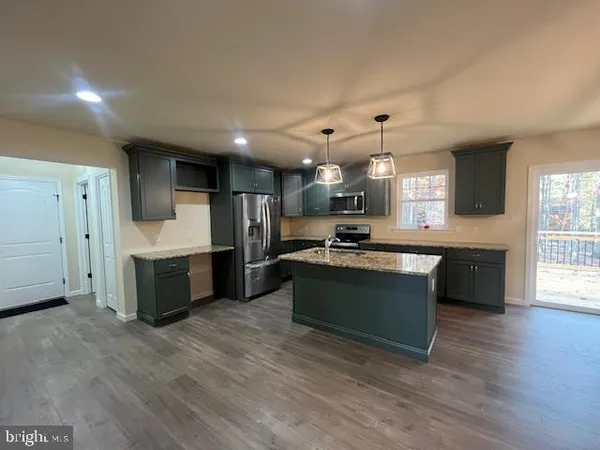 a kitchen with granite countertop a sink dishwasher a stove top oven a dining table and chairs with wooden floor