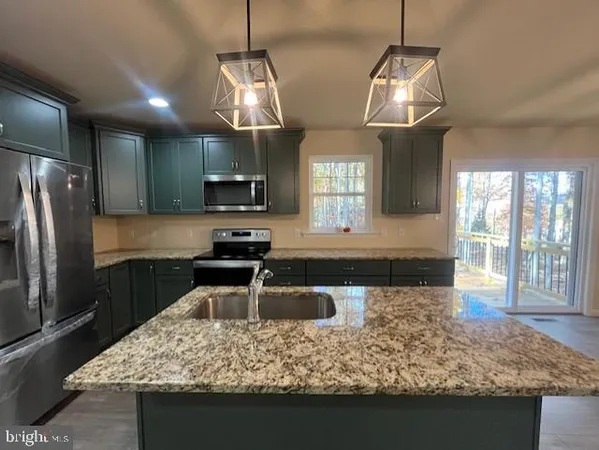 a kitchen with stainless steel appliances kitchen island granite countertop a table chairs and a chandelier