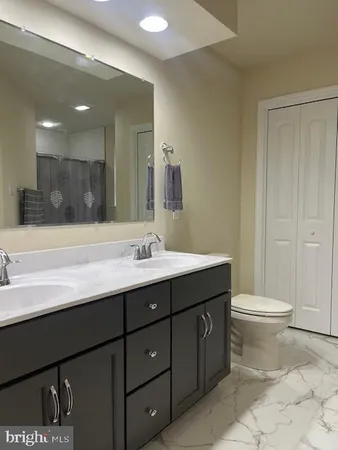 a bathroom with a double vanity sink toilet and a mirror