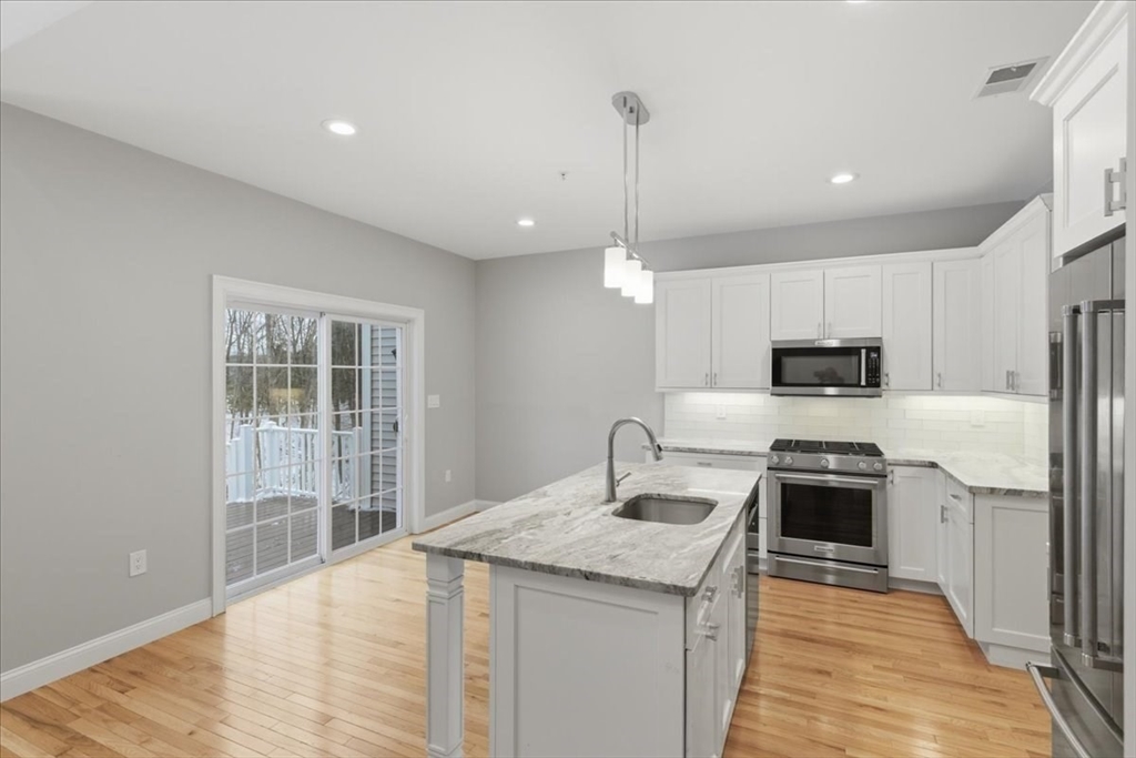 28 Eastover Road, Unit 28 Walpole, MA 02081 - Photo 5 of 34 a kitchen with kitchen island a sink stainless steel appliances and cabinets
