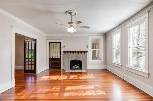 a view of an empty room with wooden floor fireplace and a window