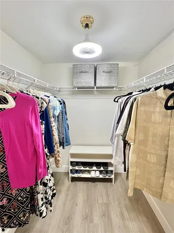 a view of walk in closet with clothes and shoes