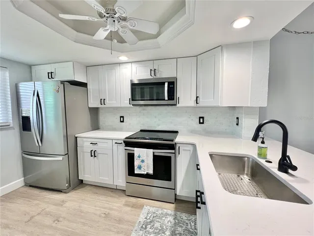 a kitchen with stainless steel appliances a stove a sink a refrigerator a microwave a sink and cabinets