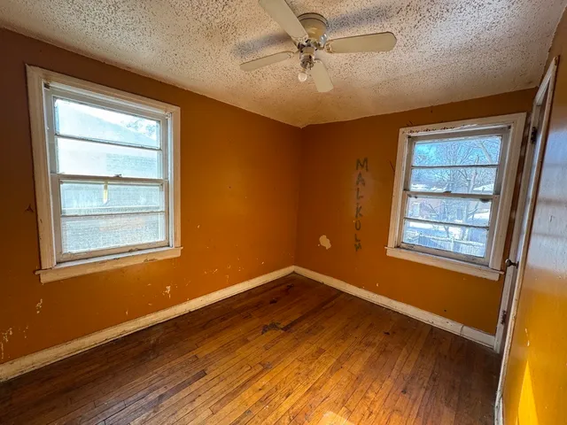 a view of an empty room with a window and wooden floor