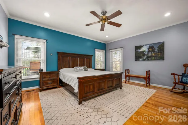 a spacious bedroom with a bed a dresser and a chandelier