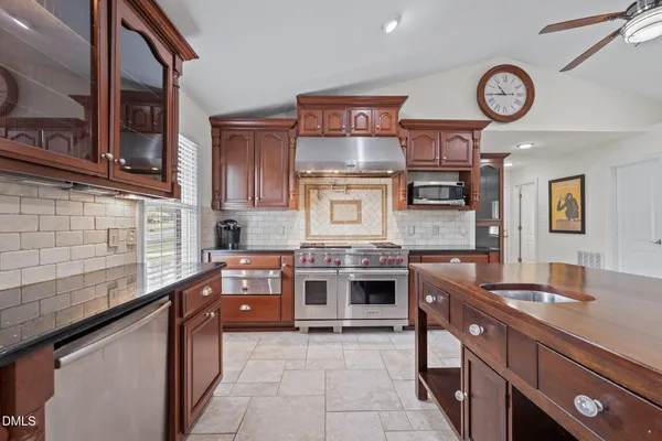 a large kitchen with stainless steel appliances granite countertop a stove and a view of living room