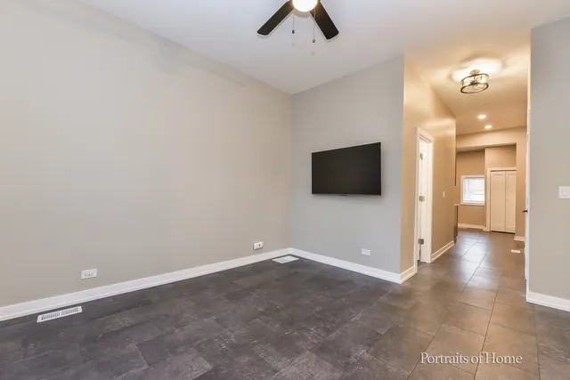 an empty room with chandelier fan and windows