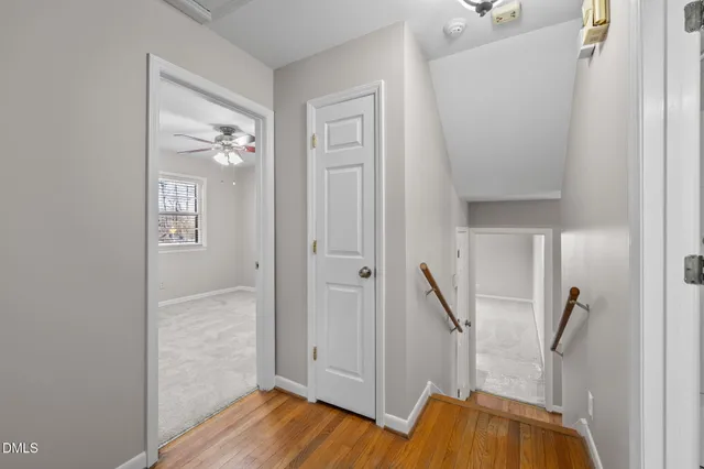 a view of an empty room with wooden floor and a ceiling fan
