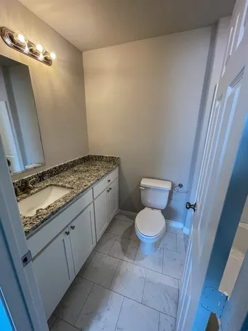 a bathroom with a granite countertop toilet and a sink