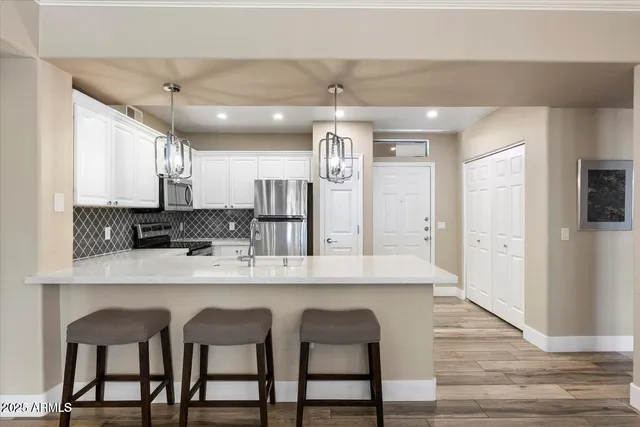 a kitchen with stainless steel appliances granite countertop a table chairs refrigerator and sink