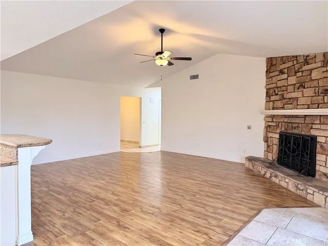 a view of a livingroom with a fireplace a ceiling fan and wooden floor
