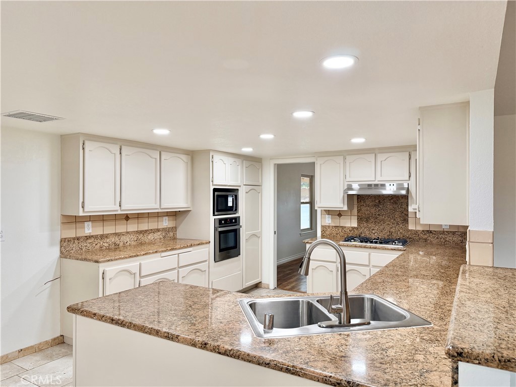 14840 Pamlico Road Apple Valley, CA 92307 - Photo 13 of 38 a kitchen with stainless steel appliances granite countertop a sink a stove and a refrigerator