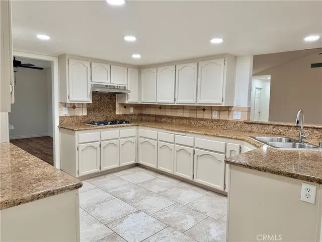 a kitchen with granite countertop a sink white cabinets and white appliances