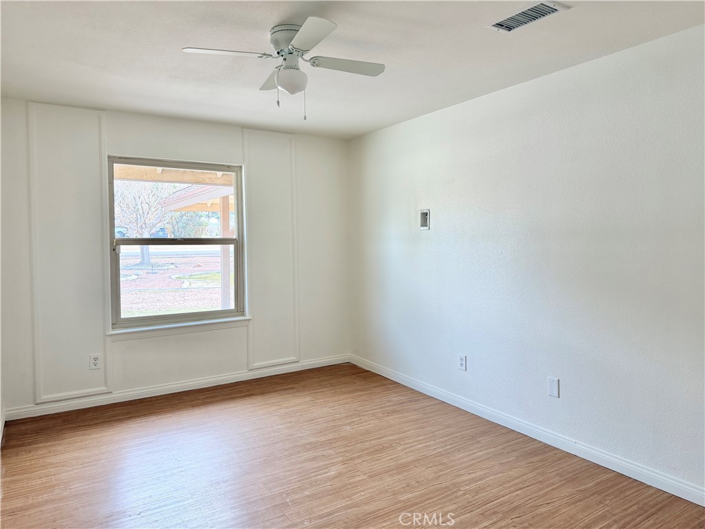 14840 Pamlico Road Apple Valley, CA 92307 - Photo 19 of 38 an empty room with wooden floor ceiling fan and windows