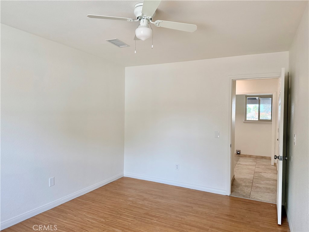 14840 Pamlico Road Apple Valley, CA 92307 - Photo 21 of 39 an empty room with wooden floor fan and windows