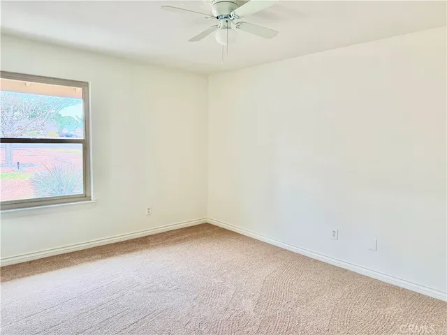an empty room with a ceiling fan and window