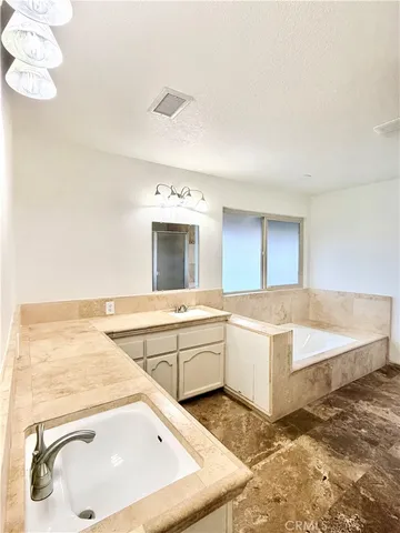 a spacious bathroom with a tub sink and mirror