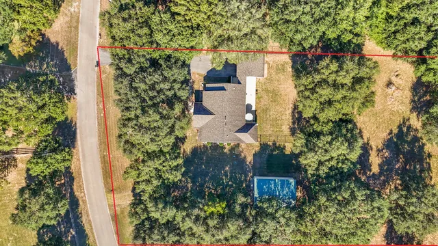 an aerial view of a house with a yard and large tree