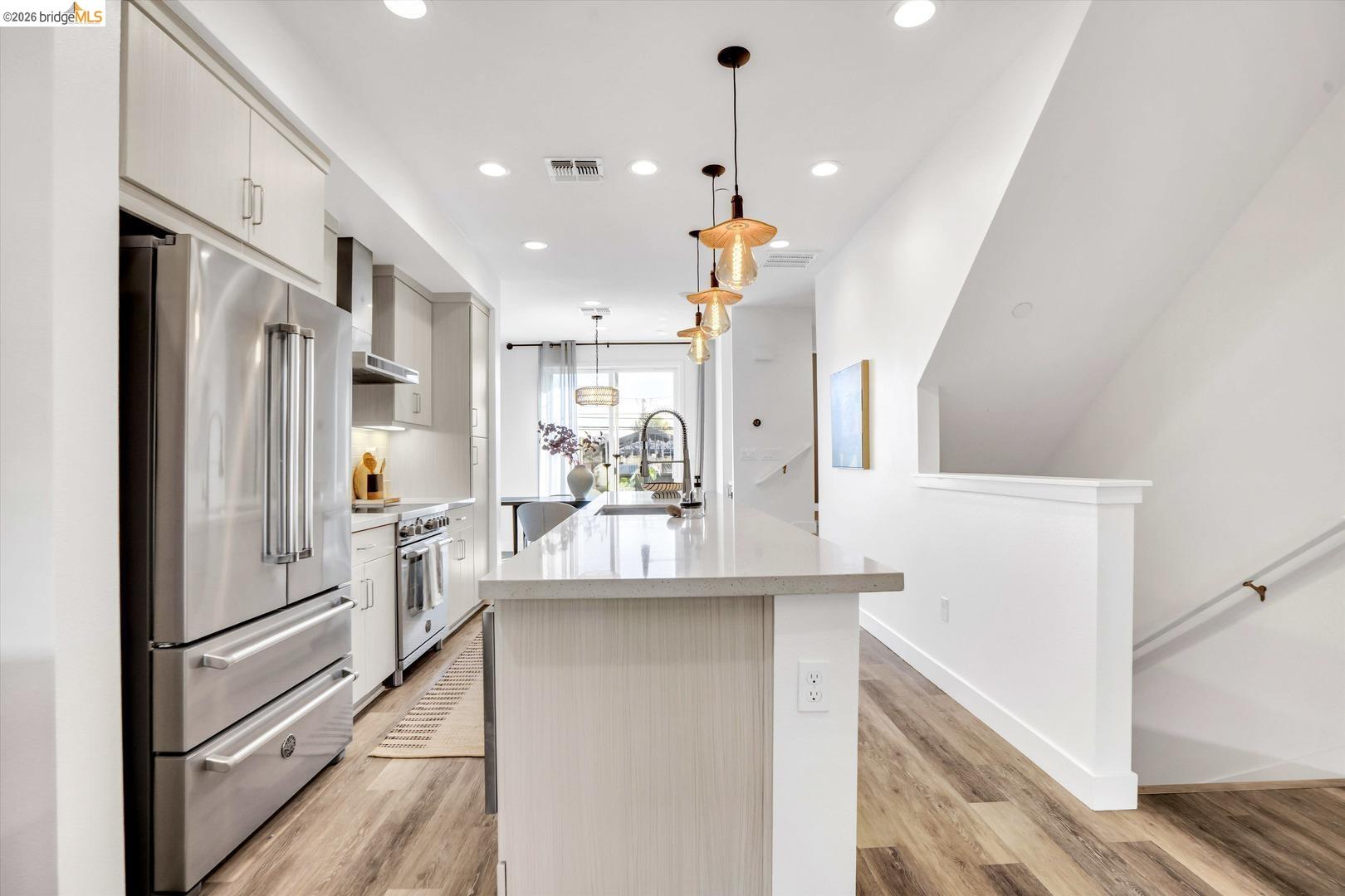 2229 Myrtle Street Oakland, CA 94607 - Photo 6 of 37 kitchen featuring stainless steel appliances, pendant lighting, light stone counters, white cabinets, and light wood-style floors