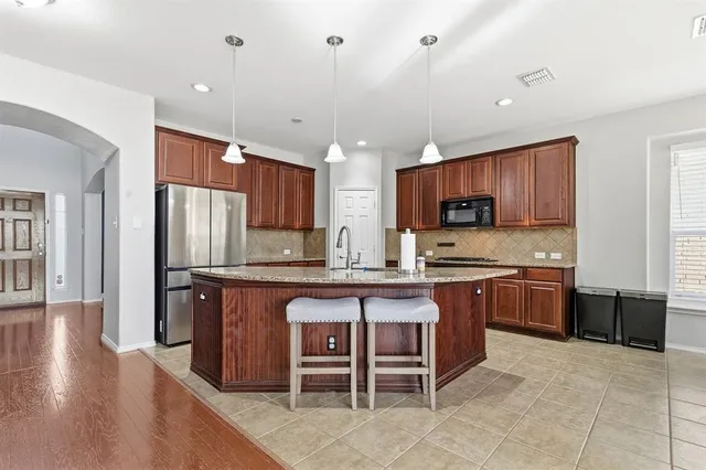 a large kitchen with stainless steel appliances wooden cabinets a stove a sink and a refrigerator