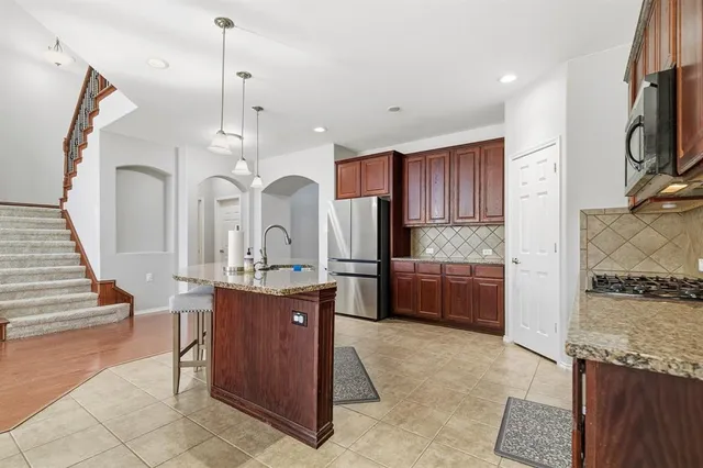 a kitchen with stainless steel appliances granite countertop a refrigerator a sink and a stove