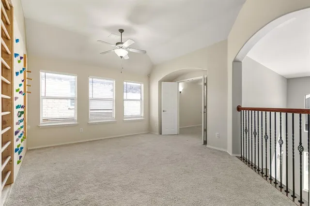 an empty room with chandelier fan and windows