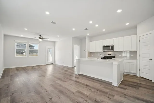 view of kitchen with stainless steel appliances refrigerator oven and white cabinets with wooden floor