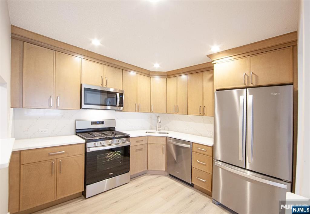a kitchen with cabinets stainless steel appliances and wooden floor