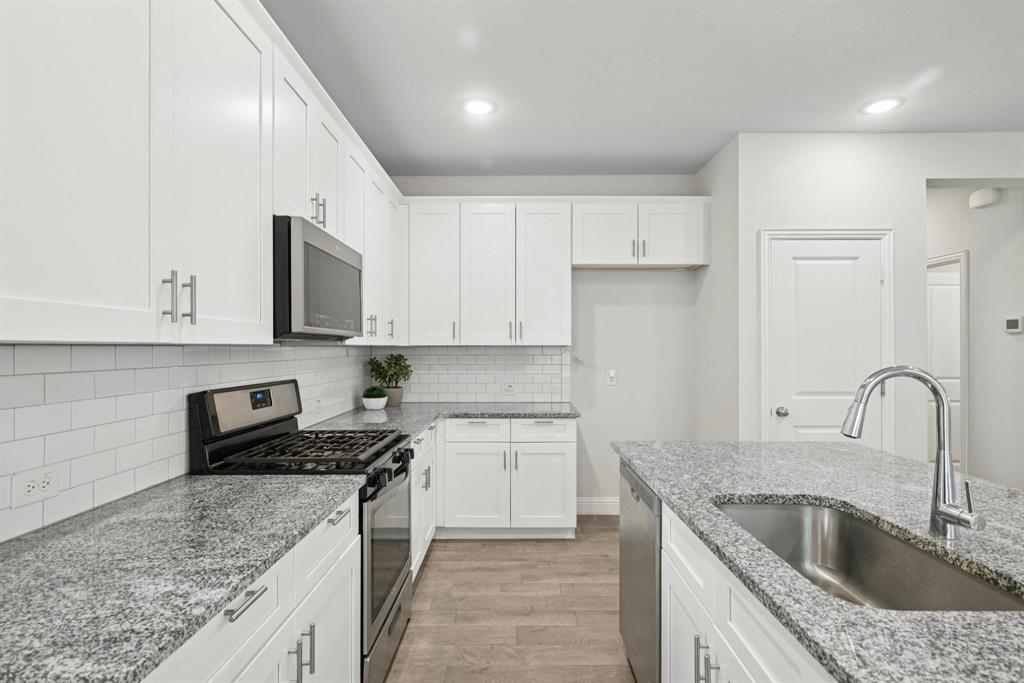 1685 Timpson Drive Forney, TX 75126 - Photo 13 of 36 a kitchen with granite countertop a sink a counter top space stainless steel appliances and cabinets