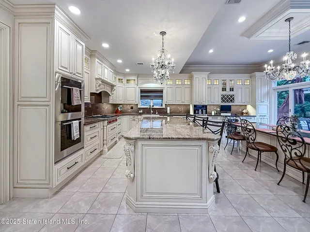 a kitchen with kitchen island granite countertop a stove oven and a chandelier